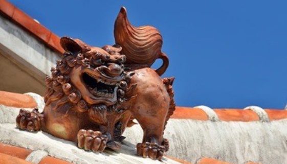 Bronze lion on top of a red tiled roof.